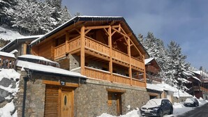 A wooden chalet with a stone facade, a balcony, and a sign indicating it is a restaurant.