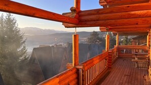 A wooden deck with a view of mountains and a lake.