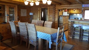 A wooden cabin interior with a dining area, kitchen, and a sign indicating 'APRE'.