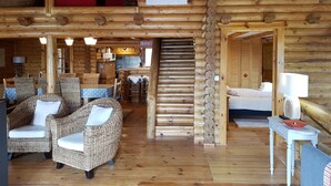 A log cabin interior with wicker furniture, a staircase, and a mounted picture of a lynx.