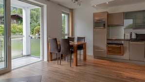 Et moderne køkken med spiseplads, store vinduer og udsigt til grønne omgivelser.