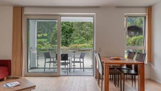 Et moderne værelse med en skydedør til en balkon med udendørs møbler.