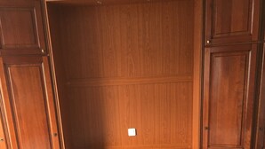 A wooden bed with a white mattress and two pillows in a room with wooden paneling and cabinets. - Attractive 32 M2 studio with 12 M2 private courtyard (Dinard)