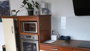 A kitchen with a built-in oven, microwave, and a coffee maker on the countertop. - Attractive 32 M2 studio with 12 M2 private courtyard (Dinard)
