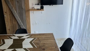 Una sala de estar moderna con una mesa de comedor de madera, un televisor montado y una puerta corrediza tipo granero.