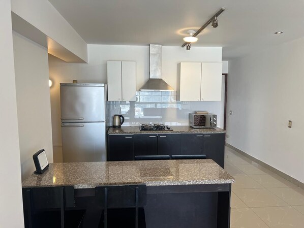 A modern kitchen with a stainless steel refrigerator, a gas stove, and dark cabinetry.