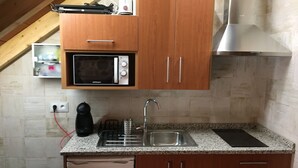 A compact kitchen with wooden cabinets, a microwave, a sink, and a dishwasher. - Apartamento Manhegu (Trevejo)