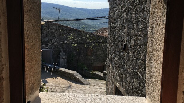 A stone building with a rustic appearance, a narrow stone staircase leading to a door, and a view of a mountainous landscape in the background. - Apartamento Manhegu (Trevejo)