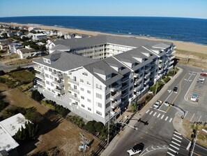 Un hôtel à plusieurs étages doté de balcons, situé près d’une plage et de l’océan.