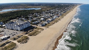 An aerial view of a coastal residential area with a beachfront, a large hotel, and a road leading to the beach. - Book Beach Haven 213D | Oceanfront Sandbridge Rental (Virginia Beach)