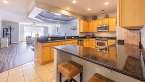 A spacious kitchen with wooden cabinets, a central island, and modern appliances. - Book Beach Haven 213D | Oceanfront Sandbridge Rental (Virginia Beach)