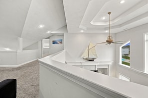 Un intérieur moderne aux couleurs claires, agrémenté d’une maquette de voilier et d’un ventilateur de plafond.