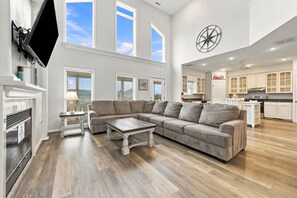 A spacious living room with a sectional sofa, a coffee table, and a fireplace. - Book Spinnaker | Semi-Oceanfront Sandbridge Vacation Rental (Virginia Beach)
