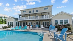 A two-story building with a balcony and a swimming pool with lounge chairs. - Book Spinnaker | Semi-Oceanfront Sandbridge Vacation Rental (Virginia Beach)