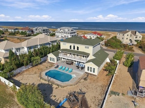 A large two-story house with a swimming pool, surrounded by a sandy beach and ocean view. - Book Spinnaker | Semi-Oceanfront Sandbridge Vacation Rental (Virginia Beach)