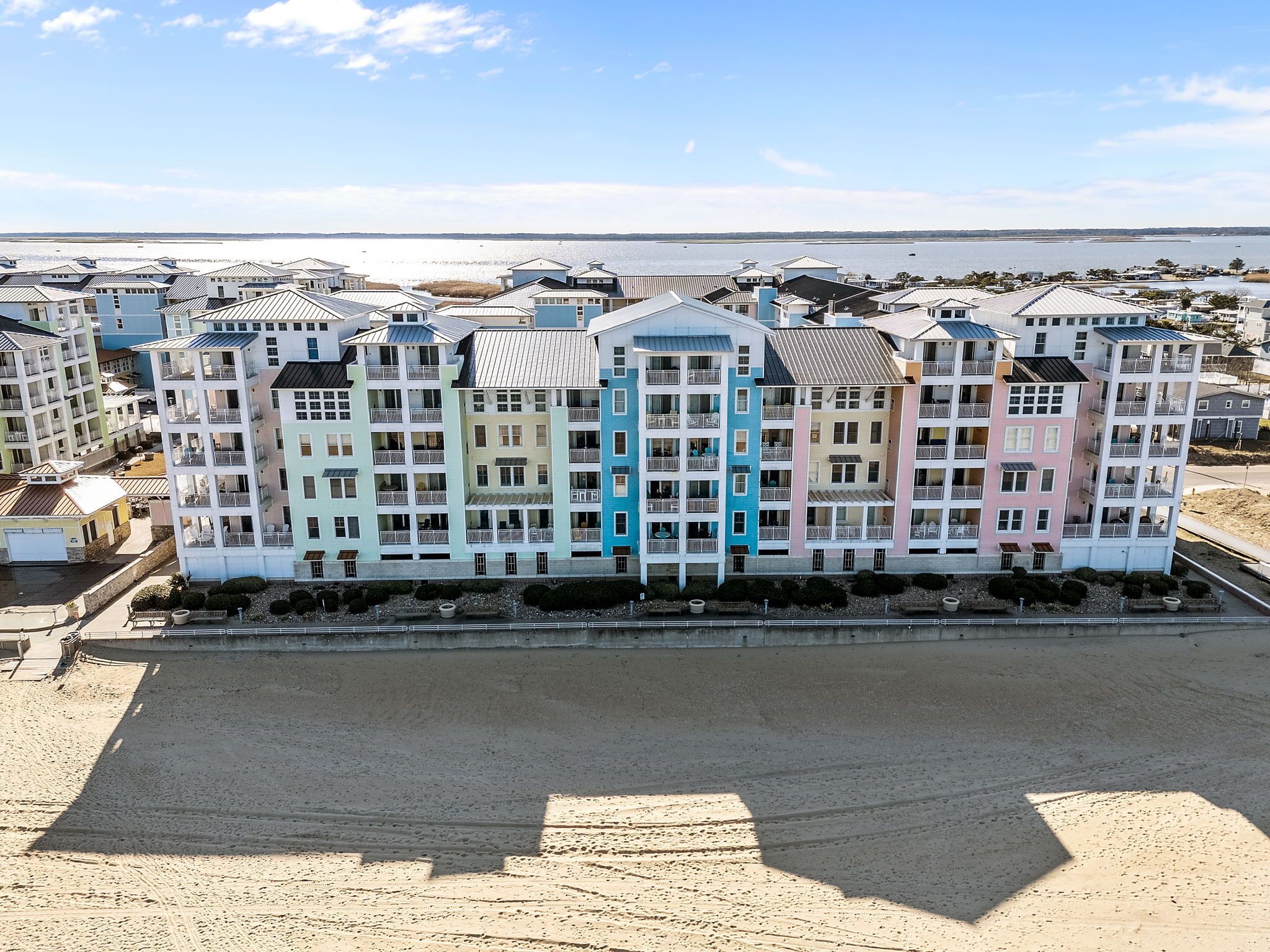 A multi-story hotel with balconies, located near a body of water.