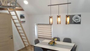 Een moderne eethoek met een houten ladder, een tafel met stoelen en hanglampen.