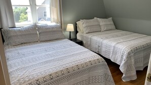 Una camera da letto con due letti, un comodino, una lampada e una finestra con tende.