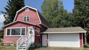 Una casa rossa con un portone garage bianco, un portico e una scalinata che conduce all'ingresso.