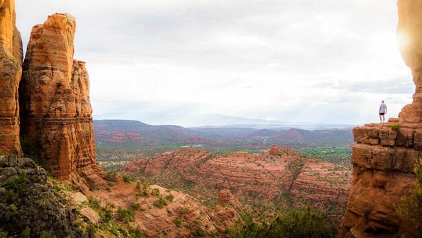 A person standing on a rock formation with a view of a canyon landscape. - Cabernet Cottage (Cottonwood)