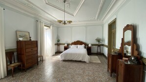 Una camera da letto con un letto grande, una cassettiera in legno, uno specchio e un lampadario.