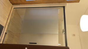 Una stanza con una porta-finestra scorrevole che dà su un balcone con tetto in legno e lucernario.