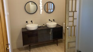 Un bagno con due specchi rotondi, un mobile vanitario in legno scuro e un lavandino bianco.