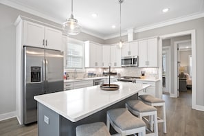 A modern kitchen with white cabinets, stainless steel appliances, and a central island with bar stools.