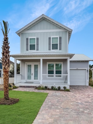 A two-story house with a covered porch, a garage, and a well-maintained lawn.