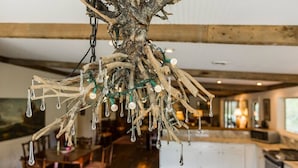 Un rustico lampadario realizzato con legno di deriva e lampadine in una cucina moderna con travi a vista e una zona pranzo.