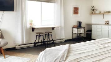 A bedroom with a bed, a desk, and a ceiling fan.