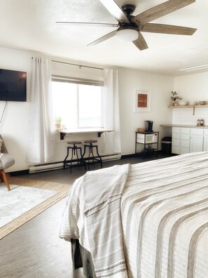 Ein Schlafzimmer mit Bett, Schreibtisch und Deckenventilator.