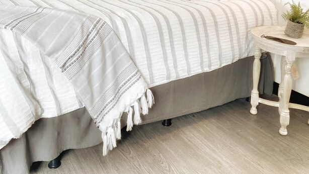 Een slaapkamer met een bed, nachtkastje en spiegel.