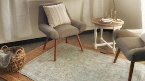 Een gezellige kamer met uitzicht op bergen door een raam, een klein rond tafeltje met kaarsen, en twee fauteuils.