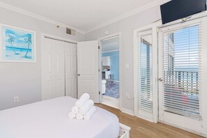 A bedroom with a bed, a door leading to a balcony, and a painting on the wall. - Palace 413 (Myrtle Beach)