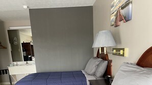A hotel room with two beds, a large mirror, a bedside table with a lamp, and a wall-mounted artwork. - The Tompkinsville Inn (Tompkinsville)