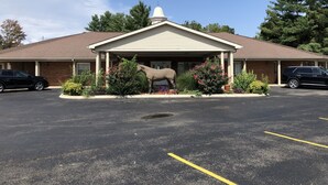 A building with a covered entrance, a horse statue in front, and a parking lot. - The Tompkinsville Inn (Tompkinsville)
