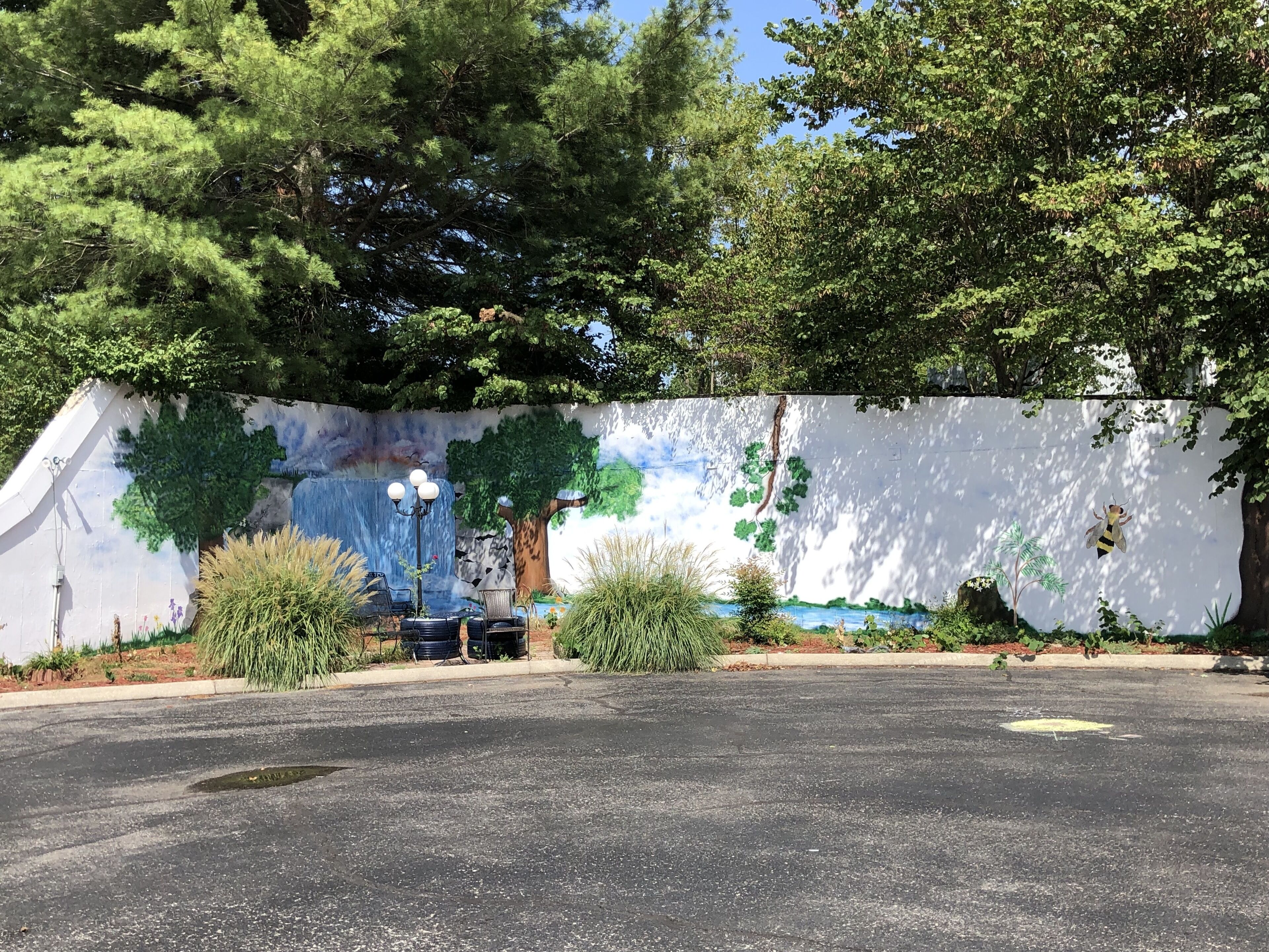 Un parking orné d’une fresque murale représentant des arbres, une cascade et une abeille.