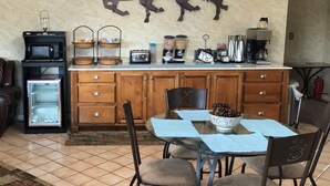 A kitchen with a microwave, toaster, and coffee maker on the counter. There is a refrigerator and a dining table with chairs. - The Tompkinsville Inn (Tompkinsville)