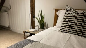 Et soveværelse med en seng, et natbord med lampe, en potteplante og en radiator.