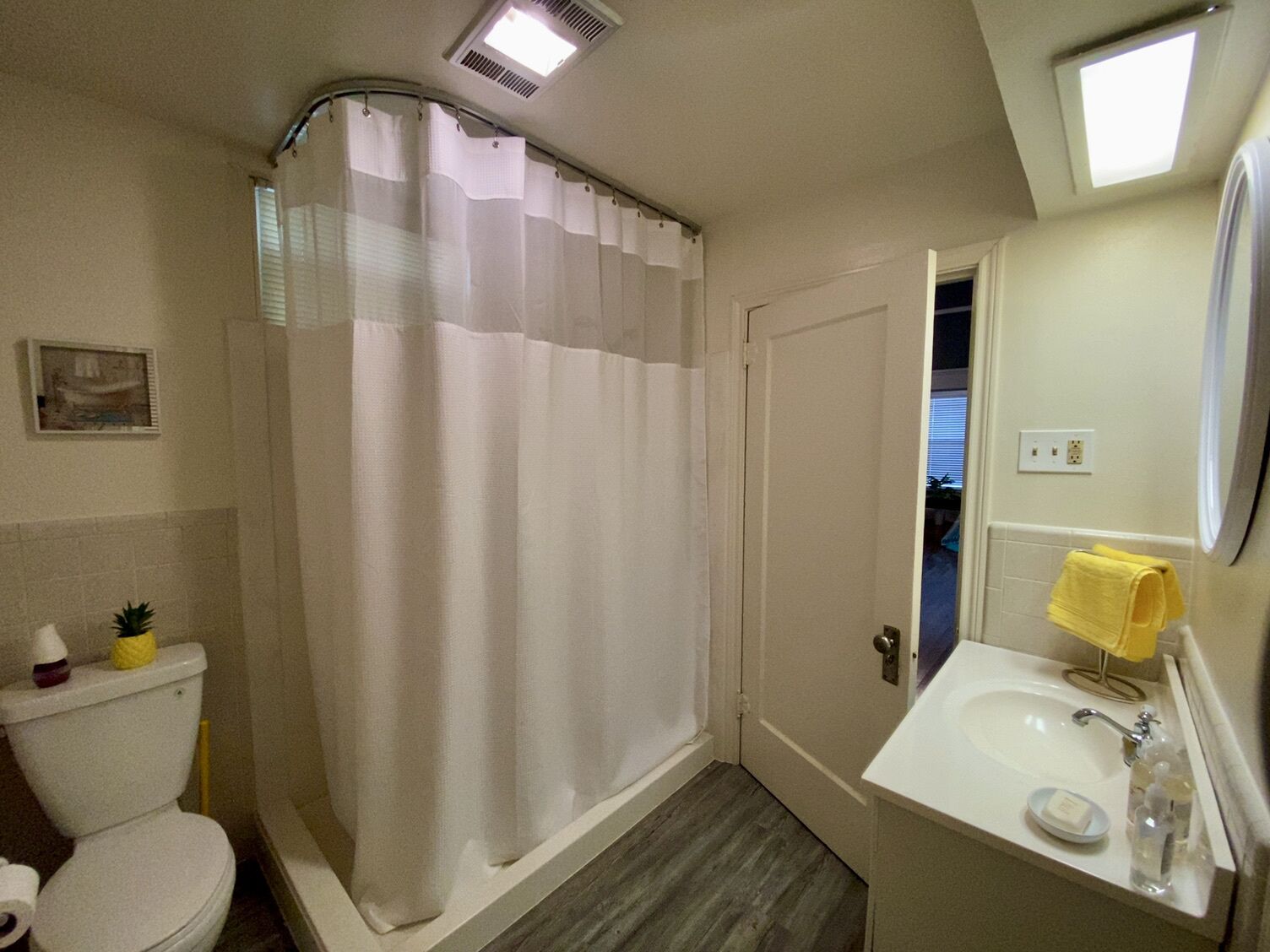 Un baño con ducha, inodoro, lavamanos y un ventanal pequeño.