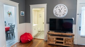 A living room with a wooden entertainment center, a large wall clock, and a flat-screen TV. - Spacious Country Living Located In The Heart Of Brenham (Brenham)