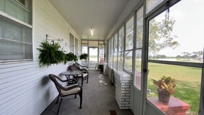 A covered porch with wicker chairs, a small table, and potted plants. - Spacious Country Living Located In The Heart Of Brenham (Brenham)