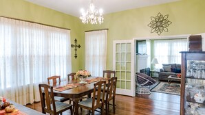 A dining area with a wooden table and chairs, a chandelier, and a decorative wall piece. - Spacious Country Living Located In The Heart Of Brenham (Brenham)