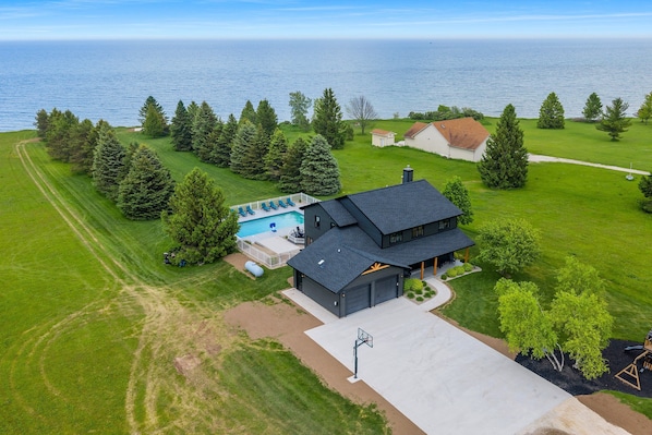 A residential property with a large garage, a swimming pool, and a view of the sea.