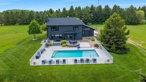 Une maison moderne à deux étages, dotée d’une piscine, d’un patio avec mobilier d’extérieur et d’une pelouse bien entretenue.