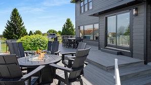 Une terrasse extérieure avec un foyer, des sièges et une vue sur la maison.