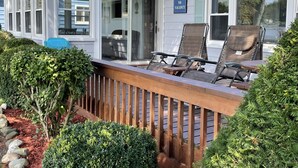 A covered outdoor seating area with a 'NO VACANCY' sign, wooden deck, and surrounding greenery.