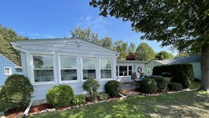 A residential house with a covered patio, a small deck, and a well-maintained lawn.