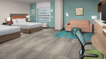 A hotel room with two beds, a sofa, a desk, and a chair.